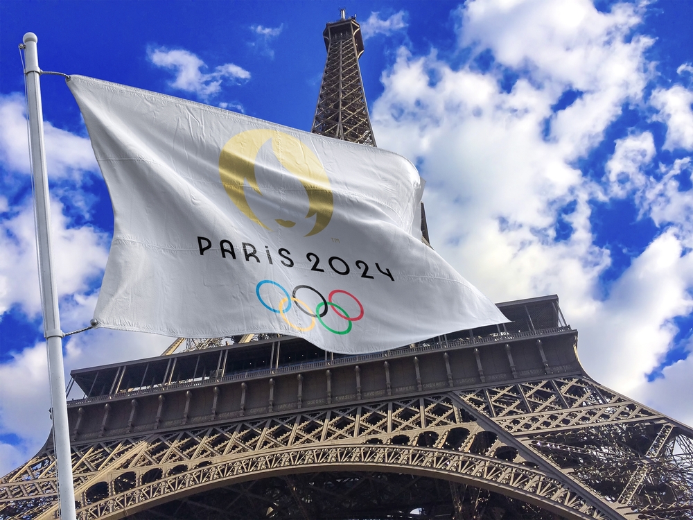 2024 Olympic flag in front of the Eiffel Tower.