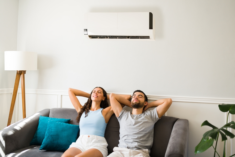A couple relaxes beneath their air conditioning vent. 