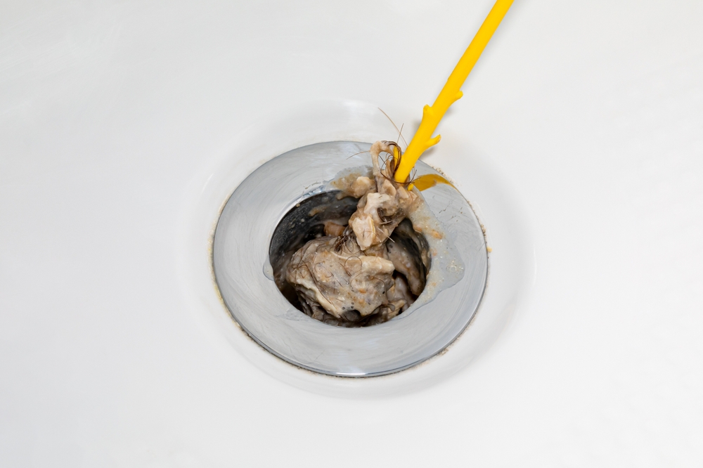 Using a drain hook to unclog a shower drain.