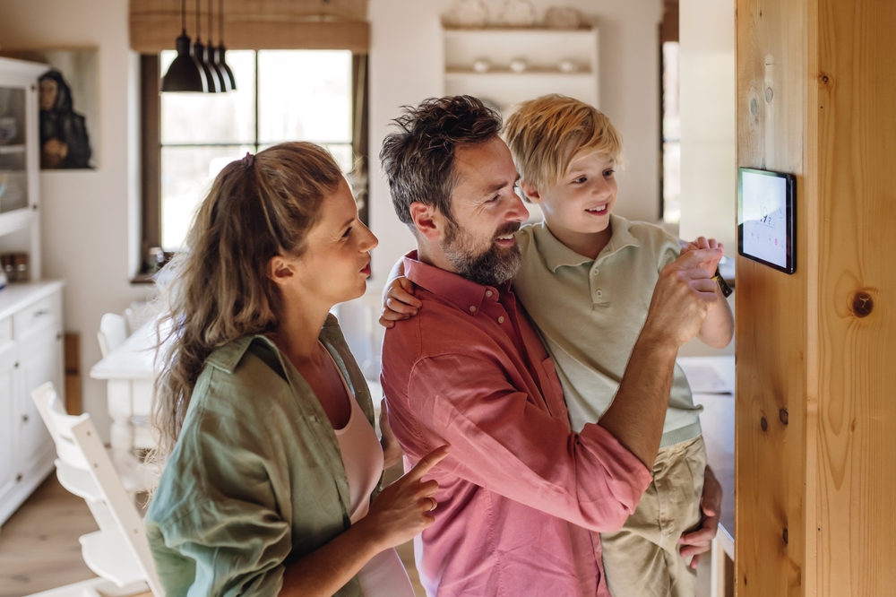 A family looks at the screen of their new smart thermostat. 