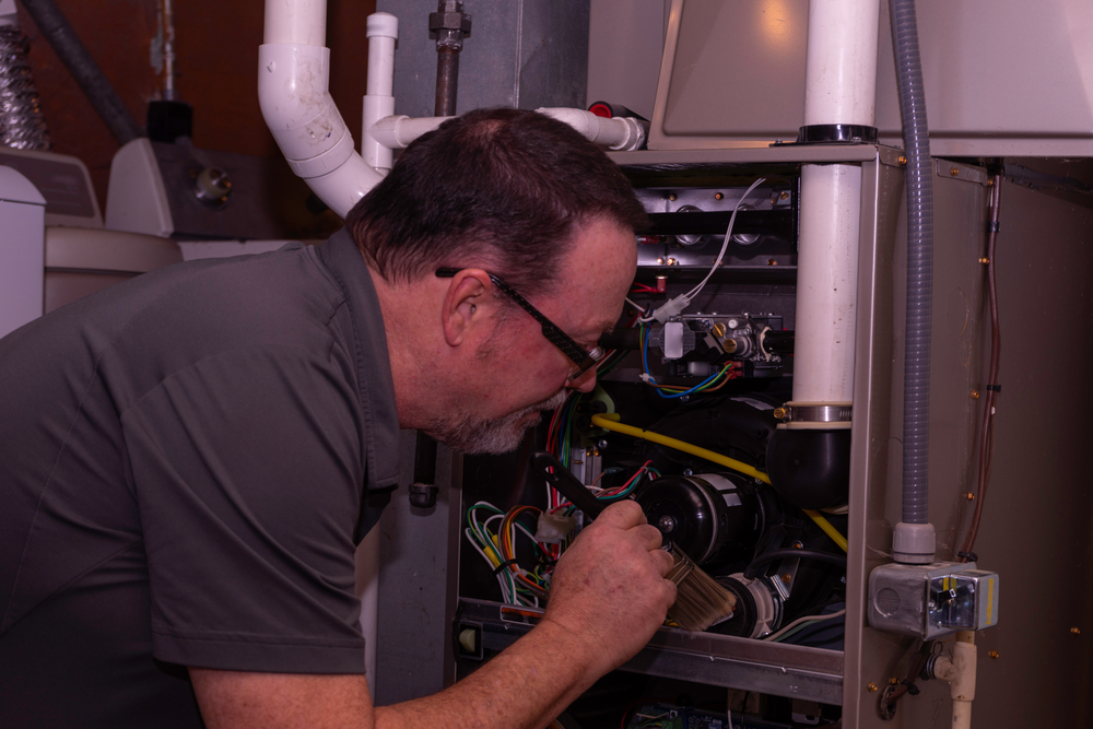 A licensed HVAC professional inspects a furnace.