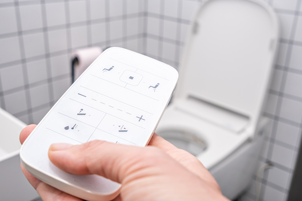 A homeowner holds the remote for a new smart toilet.