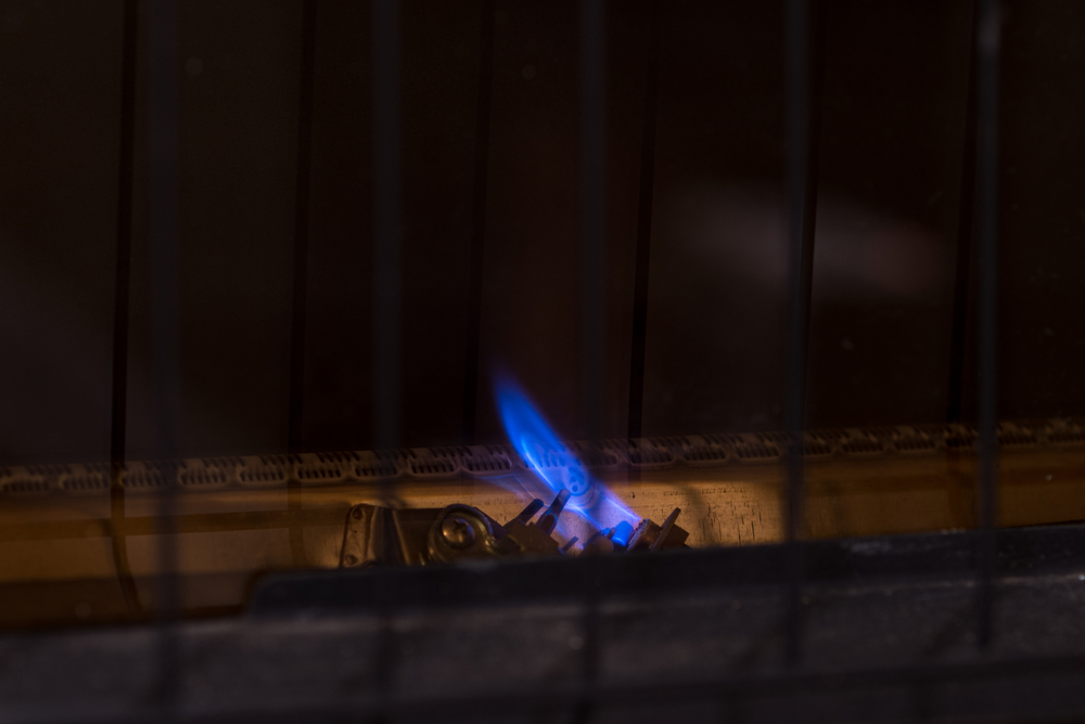 Blue pilot light glowing in furnace.