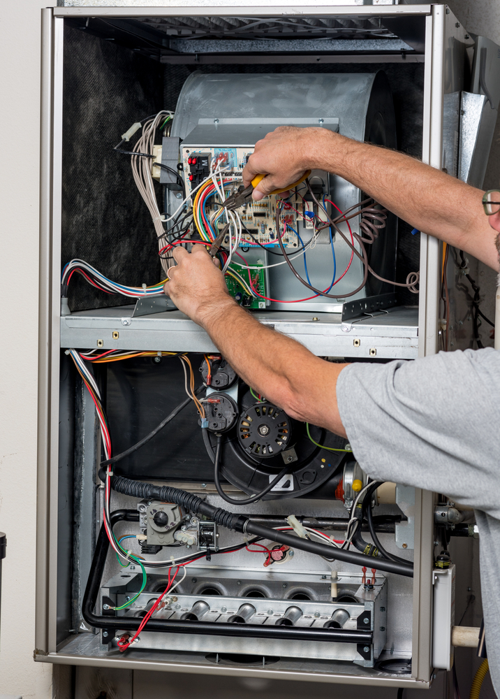 A technician inspects a furnace's wiring.